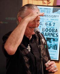 Charlie Musselwhite behind a microphone looking out to the crowd.